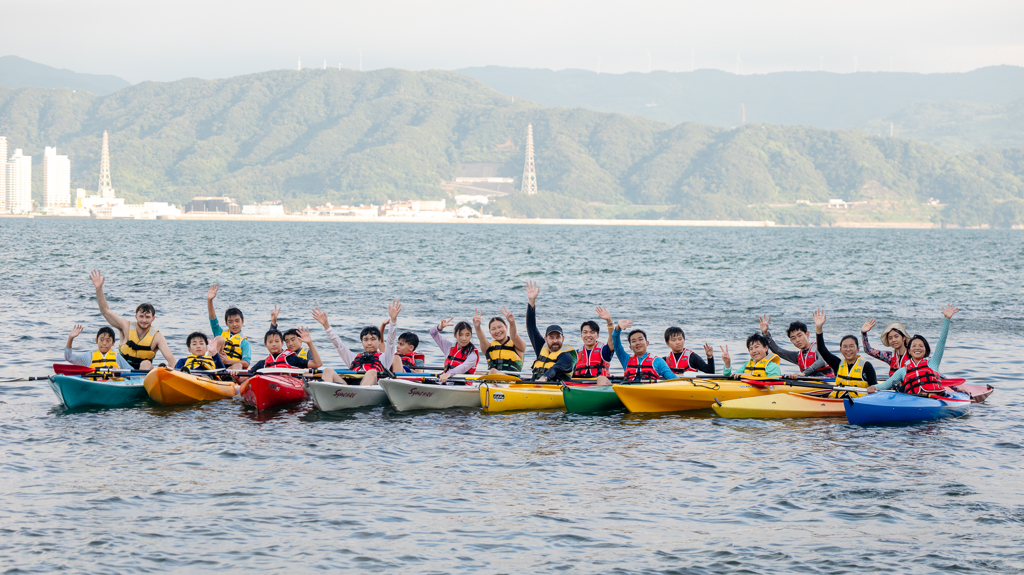 Gordonstoun Japan students during a kayak trip, waving towards the camera.